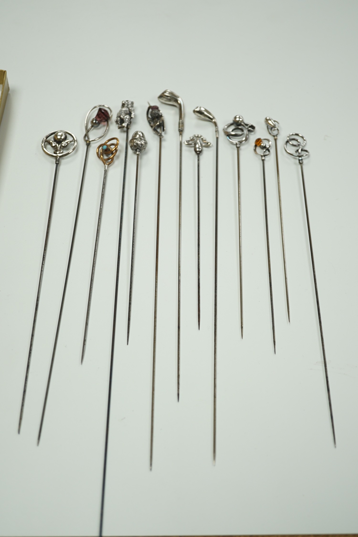 A collection of thirteen assorted early 20th century and later white or yellow metal hat pins, including four by Charles Horner including teddy bear and two silver golf club, longest 31.5cm.